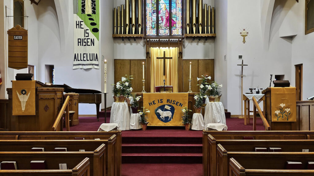 curch pews, altar, cross, stained glass, and red carpet.